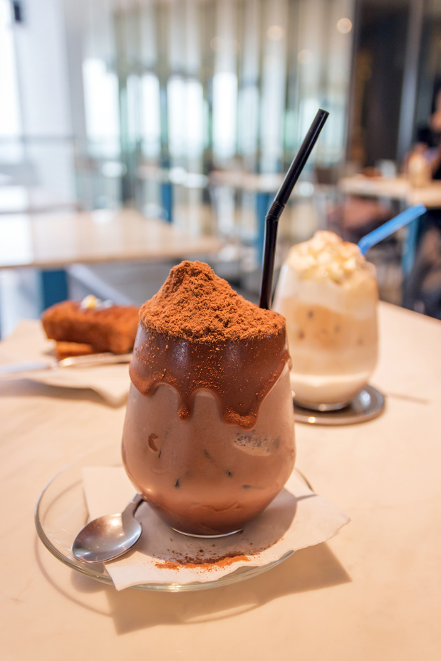 Glass of iced chocolate on marble table at minimalist café.